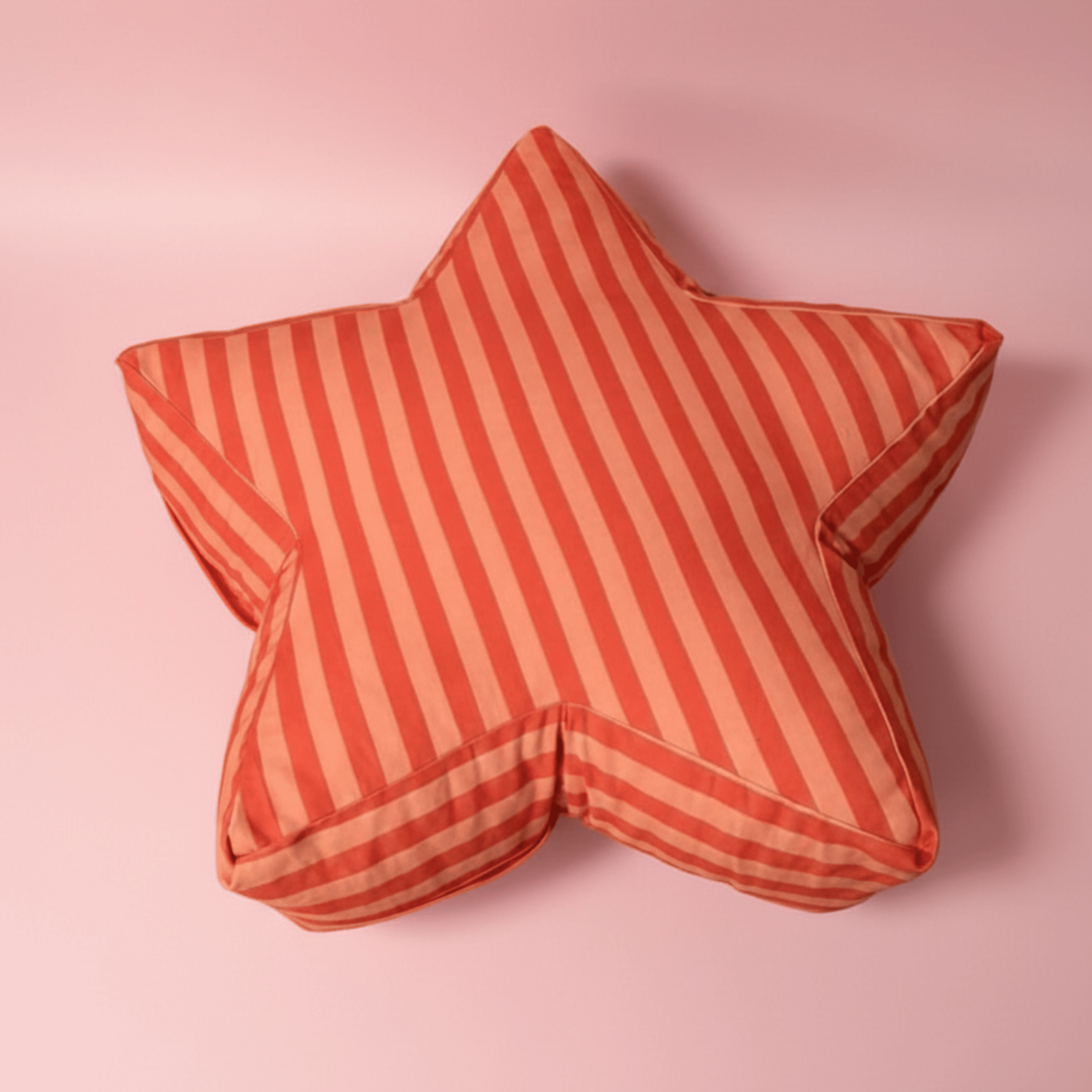 Large star-shaped floor cushion called the Superstar Crash Pad, featuring red and orange stripes on a light pink background.